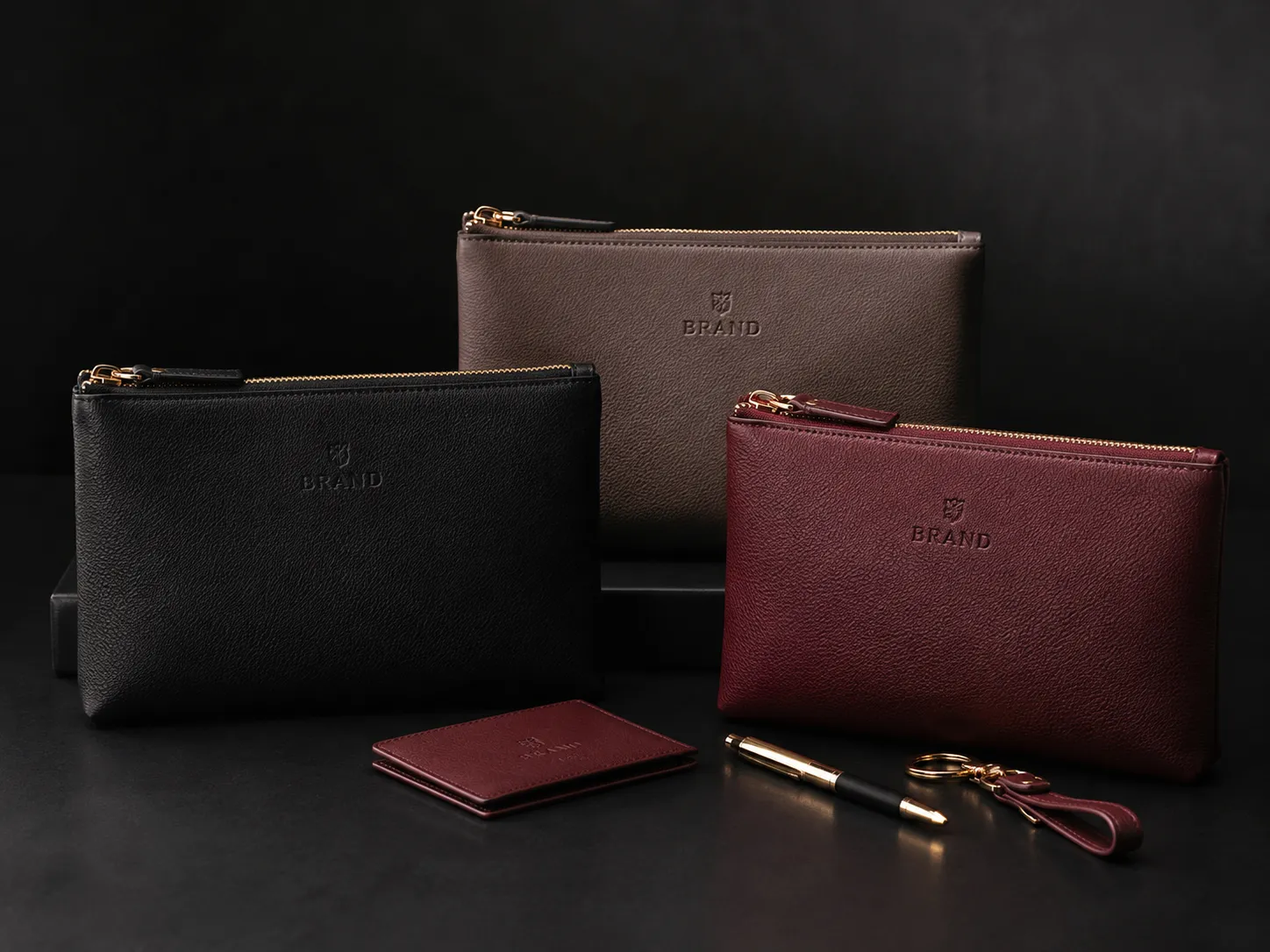 Pochette in pelle nera, taupe e bordeaux con logo in rilievo